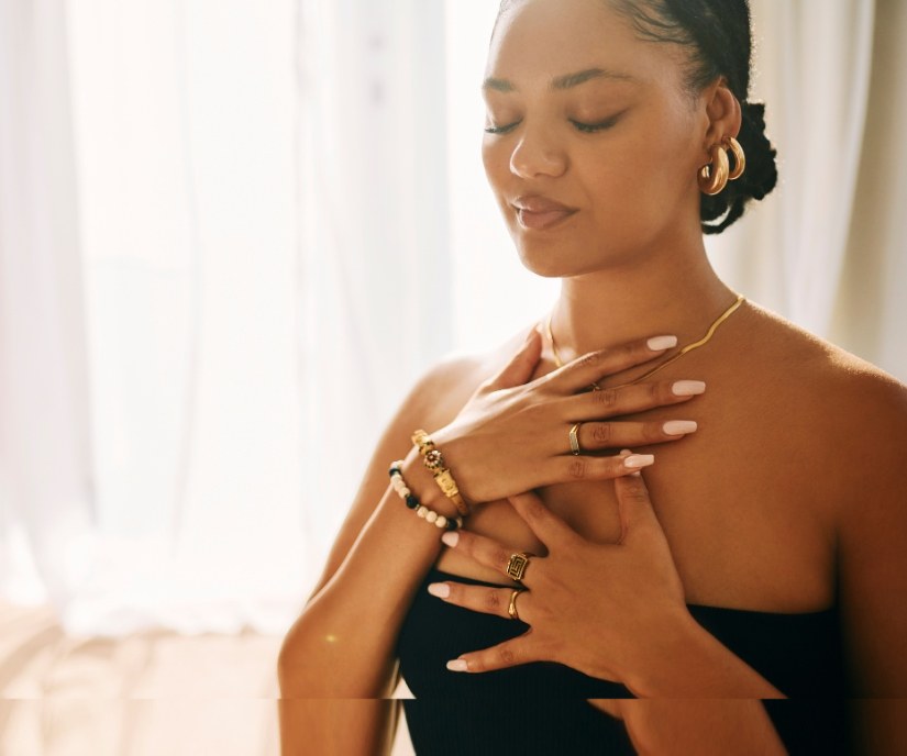 A woman with her hands resting gently on her chest, eyes closed, taking a slow, steadying breath